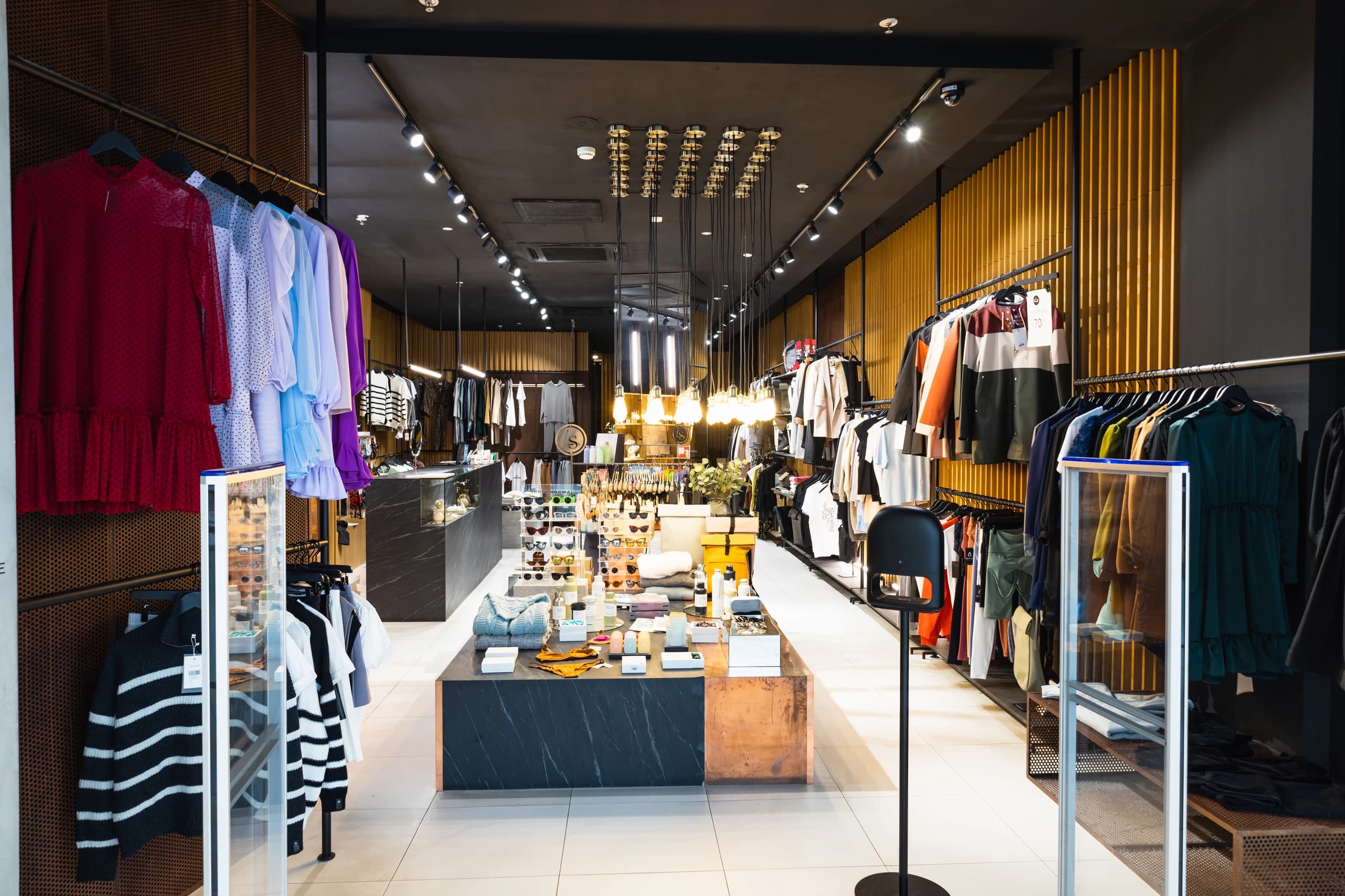 Racks of clothing inside a fashion store, with a clear aisle between them