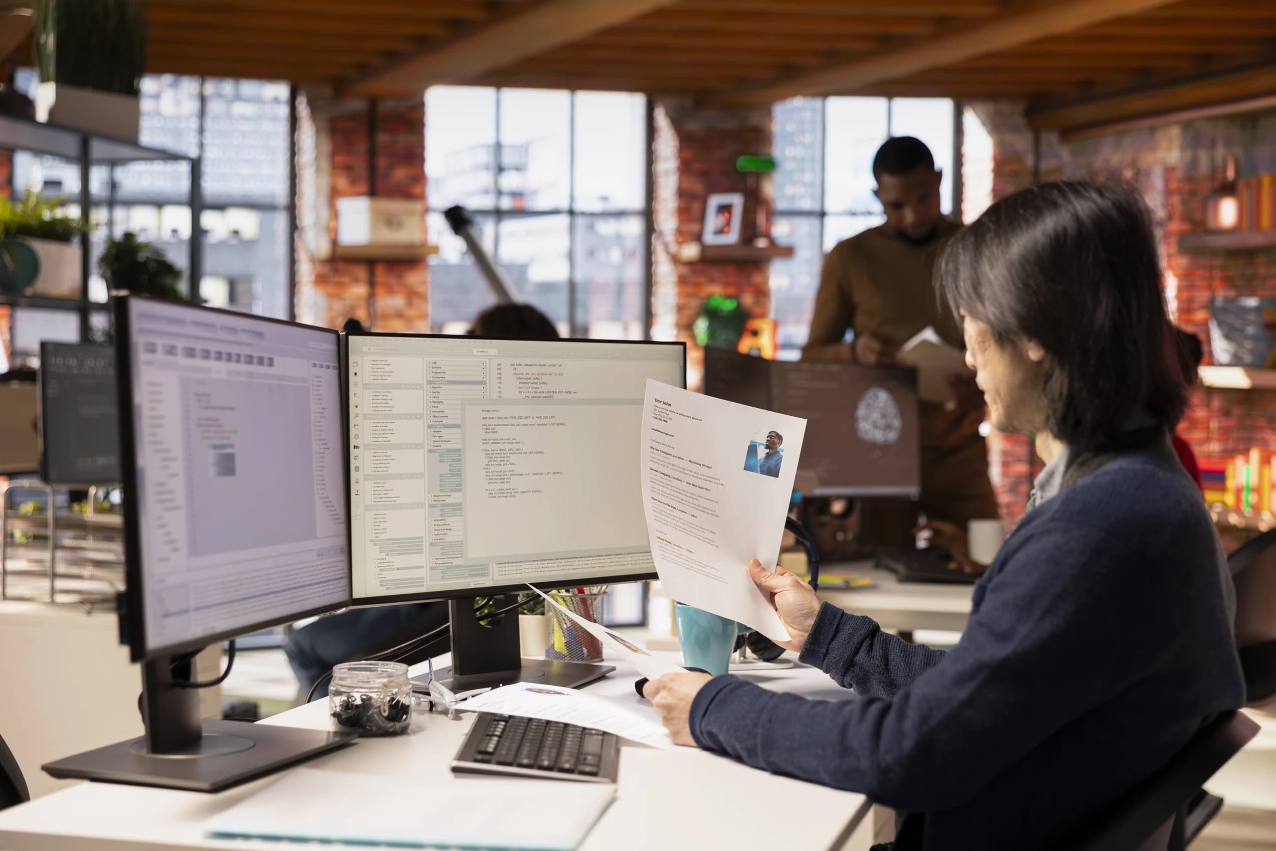 An HR executive working through employee records at a two-screen desk