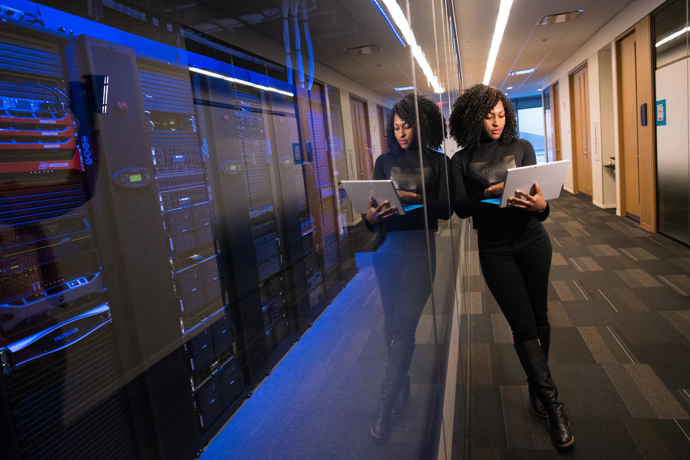An engineer working a tablet in a blue-lit data hall