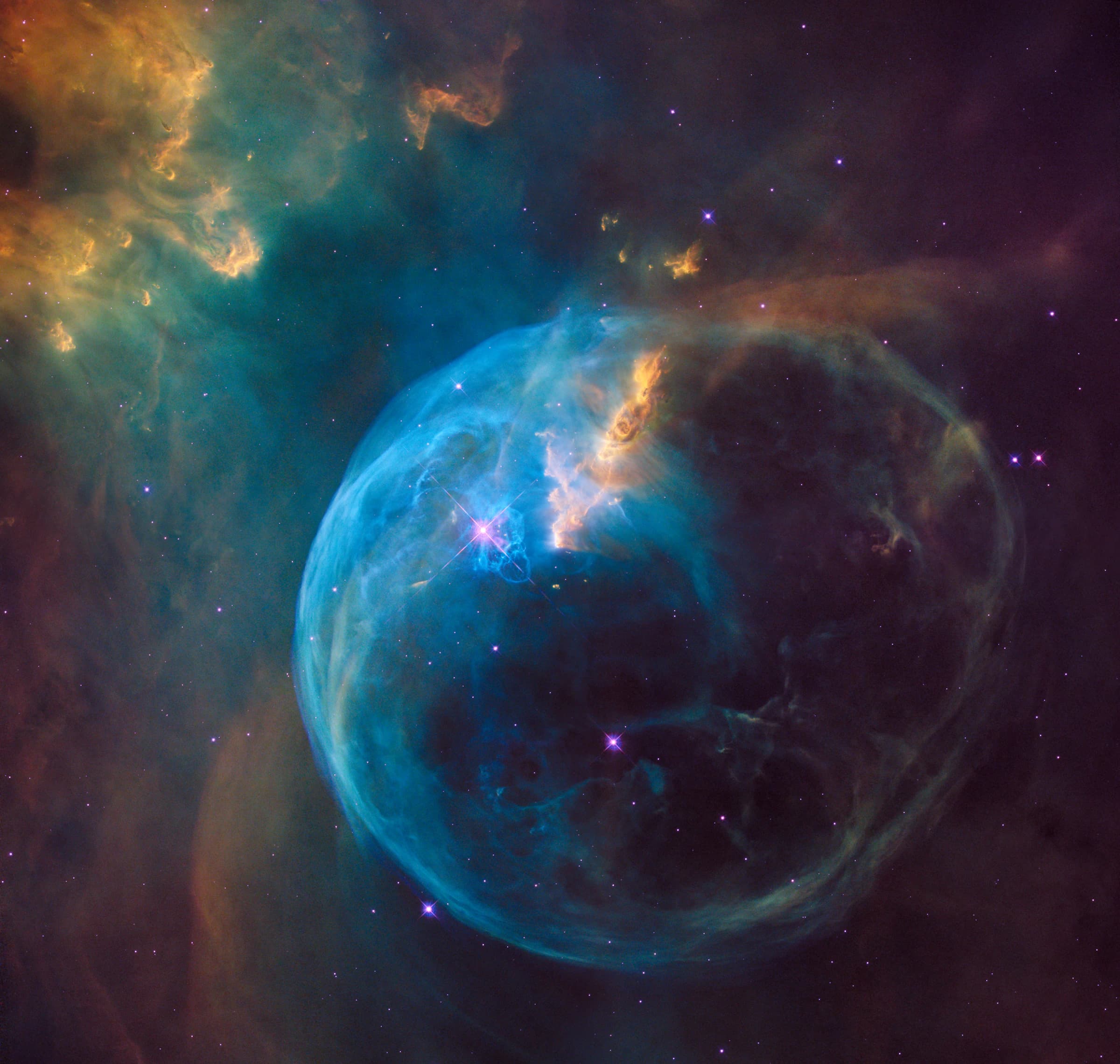 An emission nebula shell in cyan and gold against deep field stars