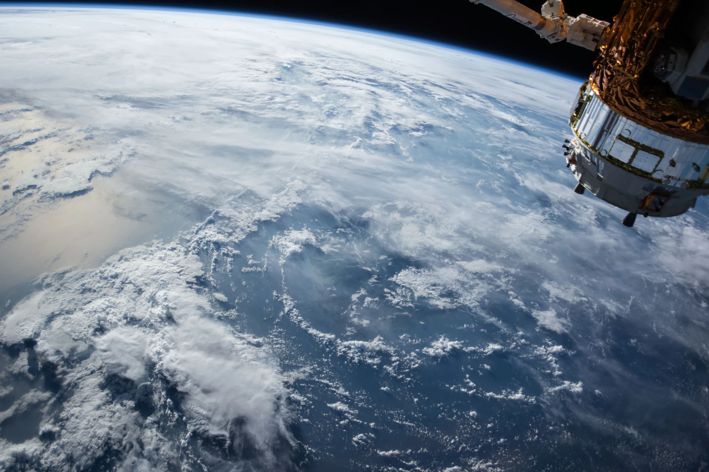 Earth's limb photographed from a station cupola with a docked module in frame