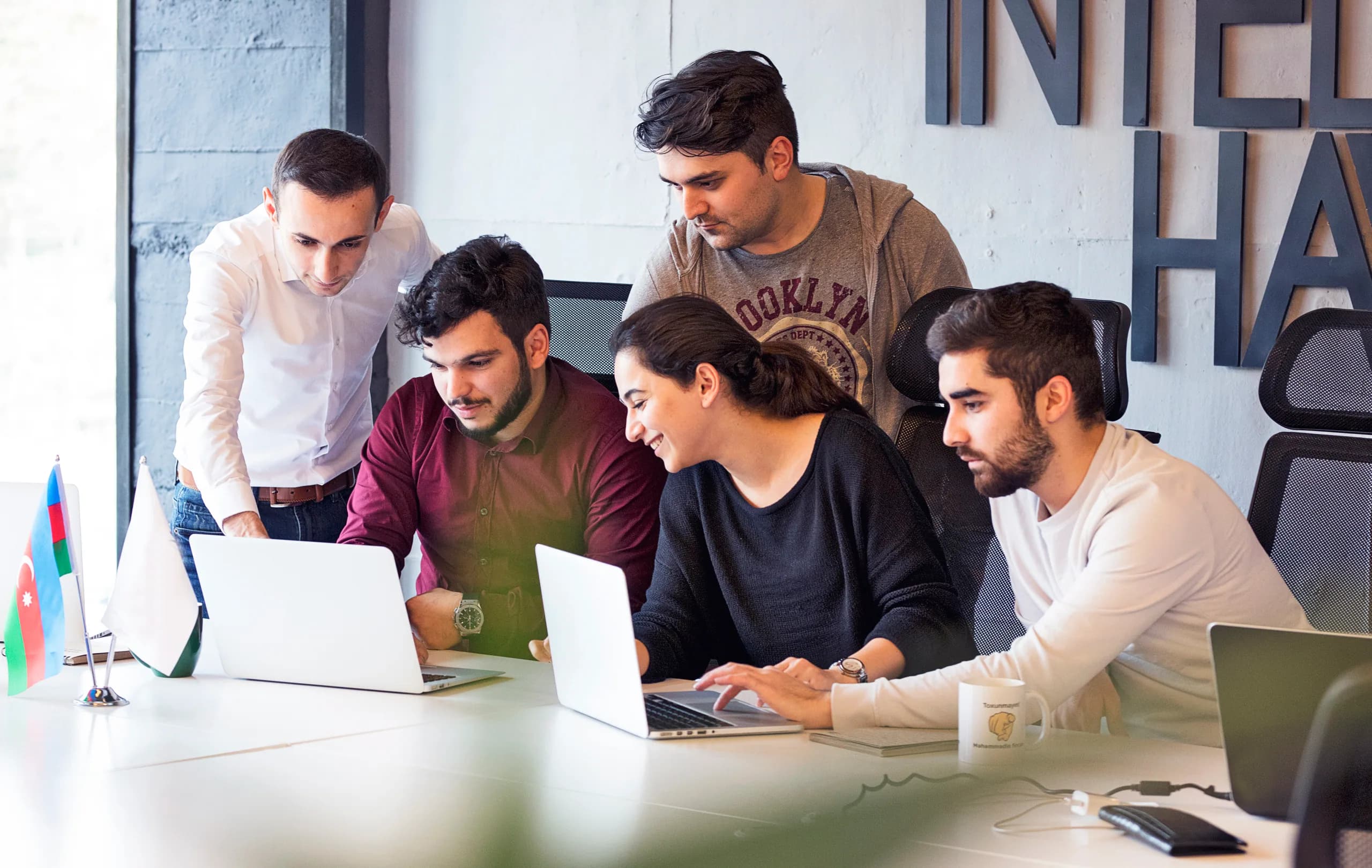 Colleagues around a table, talking through a project on their laptops