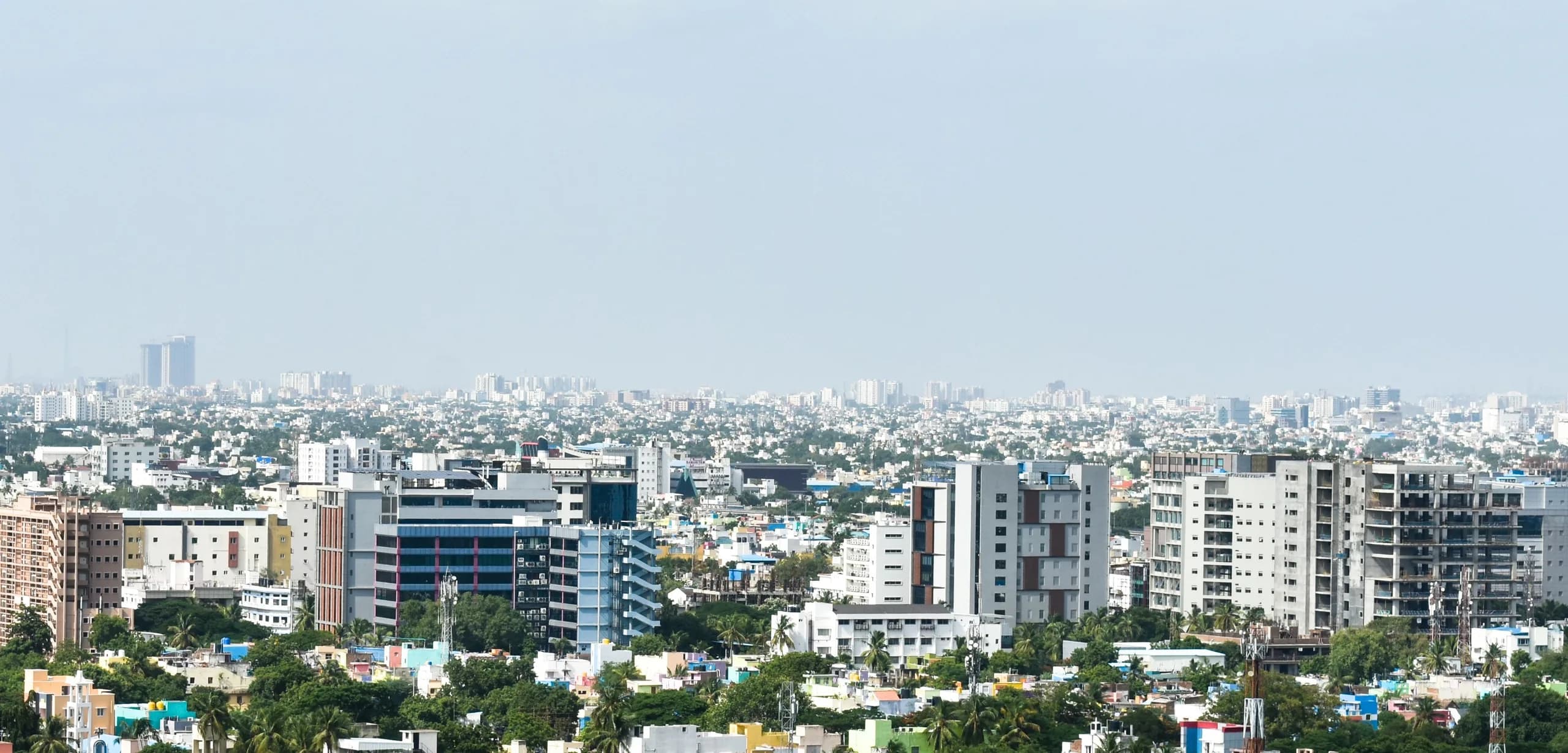 Daytime view across Chennai: mid-rise offices and apartments rising above low-rise neighbourhoods to a hazy horizon