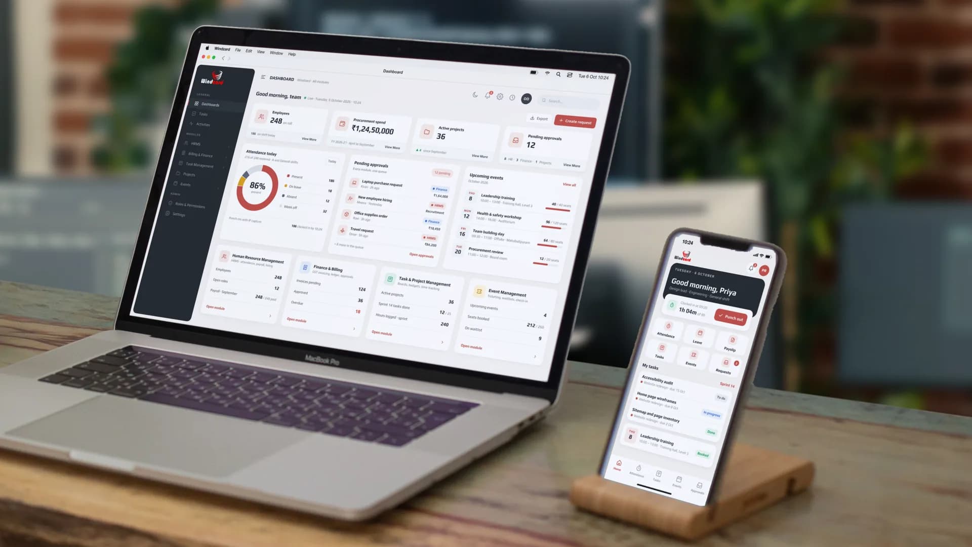 The Windzard platform dashboard: 248 employees, ₹1,24,50,000 of procurement spend, 36 active projects and 12 pending approvals, over the four modules it runs — HRMS, Finance & Billing, Task & Project Management and Event Management — on a MacBook, with the staff app's home on an iPhone beside it