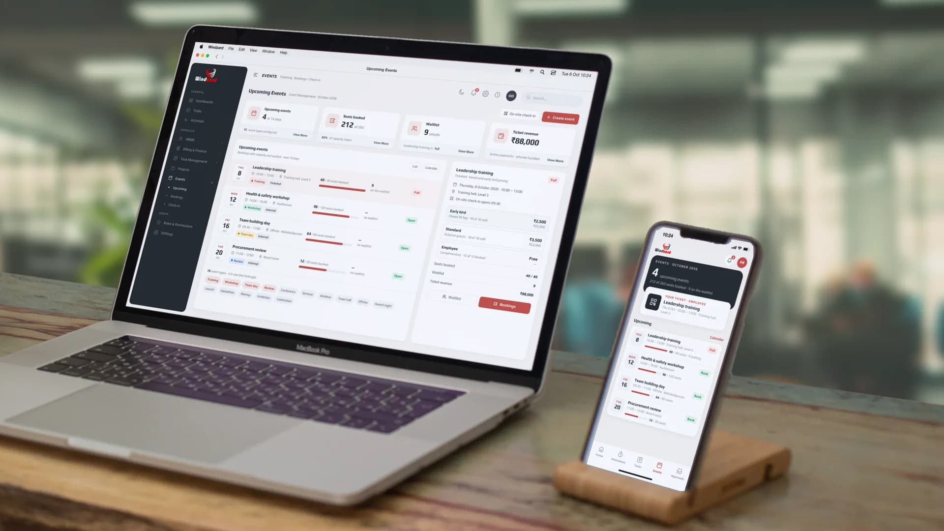 The upcoming events list — leadership training, a health and safety workshop, a team building day and a procurement review — with dates, times and seats booked against each — on a MacBook, with the staff app's event list on an iPhone