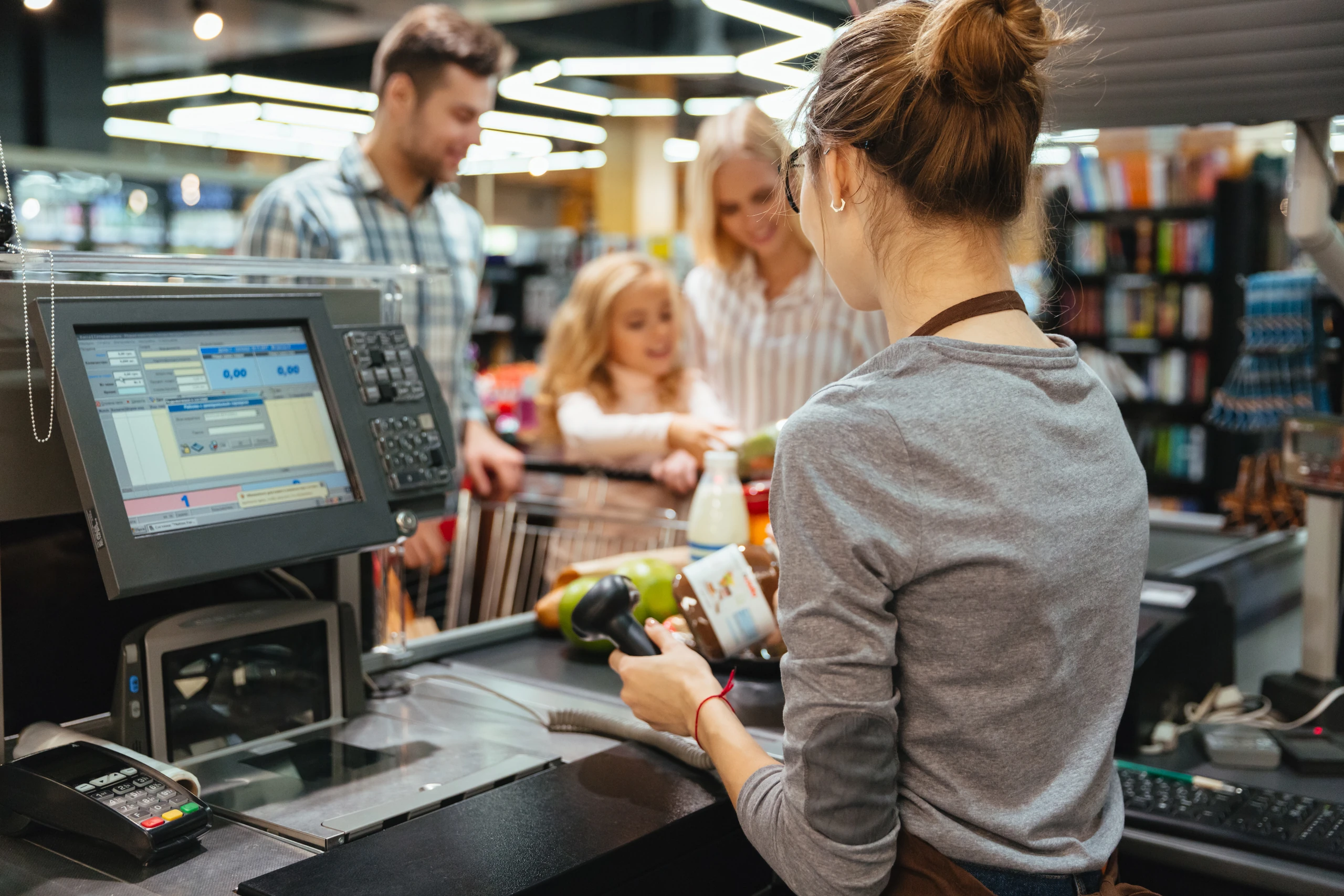 Cashier scanning groceries at a supermarket point-of-sale terminal